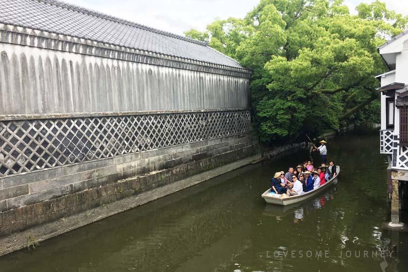 This is a punting boat cruise in Yanagawa. A boat carrying tourists is sailing along the moat in Yanagawa City. On the left is a white wall called the namako wall.