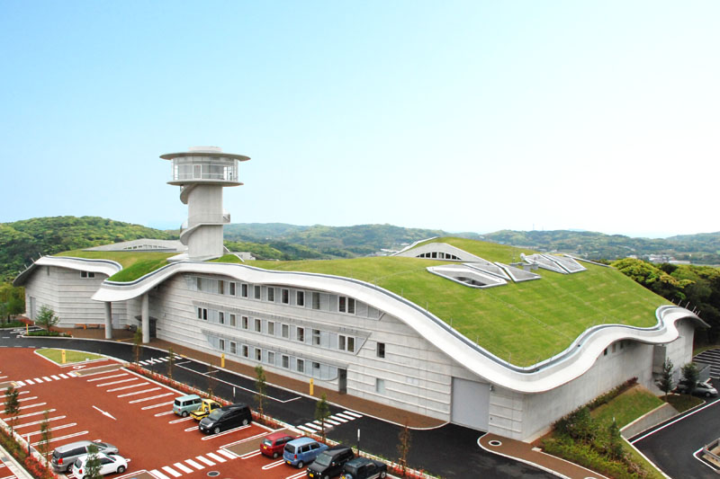 壱岐市立一支国博物館の全景です。博物館の建物は、白い壁と曲面の屋根が特徴的で、屋根には芝が植えられて緑が輝いています。