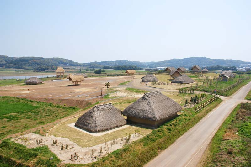 This is the Harunotsuji Archeological Site in the Restored Imperial Capital Park. More than a dozen wooden structures with thatched roofs, including turrets and high-floored buildings, have been restored on the flat land.