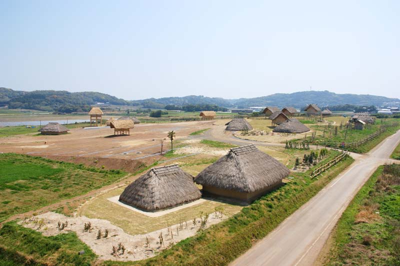 一支国王都復元公園にある原の辻遺跡です。平らな土地に、櫓、高床式建物など茅葺屋根の木造建築物が十数棟復元されています。