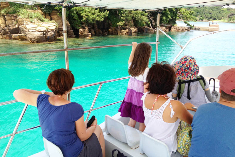 This is the inside of a ferry crossing from Katsumoto Town to Tatsuno Island. The ferry is approaching Tatsuno Island, and the passengers, including children, keep looking at the sea, impressed by the beauty of the cobalt blue colored sea.