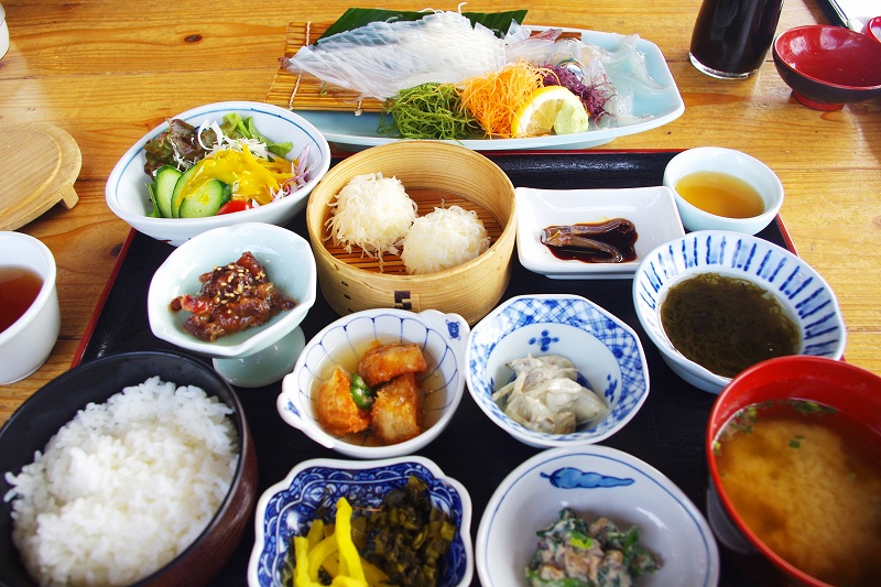 This is the Live Squid Set Meal at Ika Honke Honten, a recommended squid restaurant in Yobuko, Karatsu. The dish includes live squid sashimi, squid siumai, mozuku seaweed, simmered vegetables, raw vegetables, rice, and miso soup.