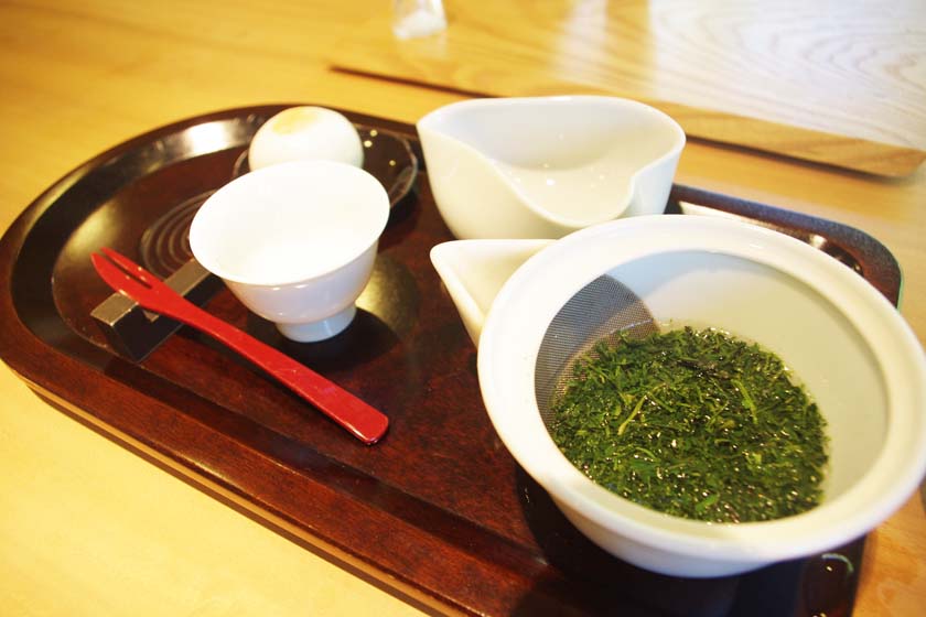 This is gyokuro, a high-grade green tea at Seisui-an. On the right is a teapot filled with gyokuro, and on the left is a teacup. White Japanese sweets are placed behind the tea bowl.