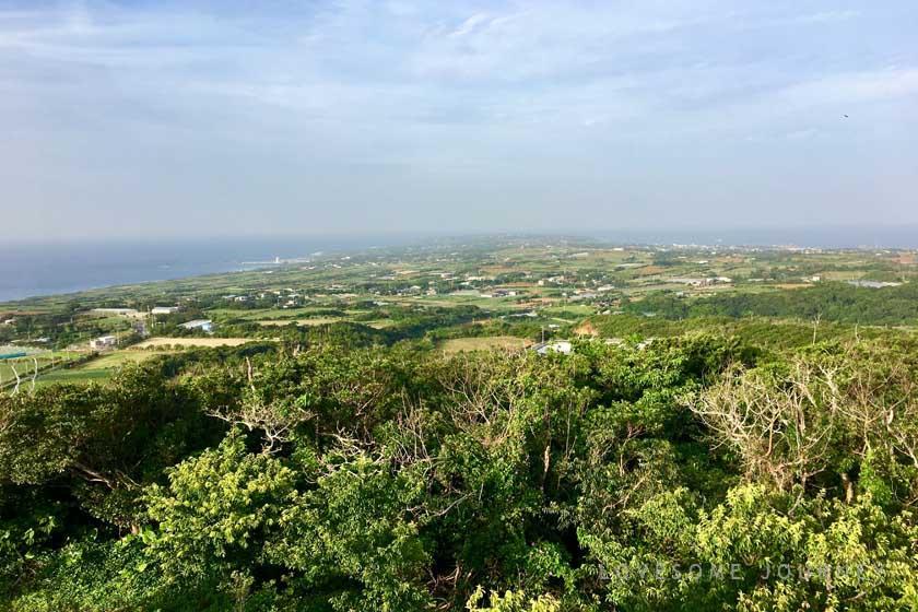 沖永良部島にある越山公園の展望台からの眺めです。沖永良部島の緑の大地、赤土の畑、美しい海の青色のコントラストを楽しむことができます。