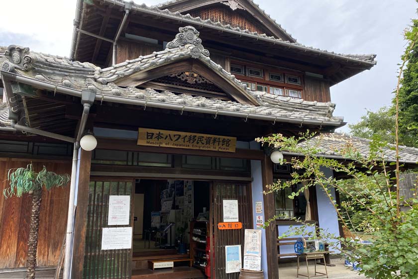 周防大島にある日本ハワイ移民資料館です。木造の日本家屋です。入り口の上部に、「日本ハワイ移民資料館」と筆で書かれた看板がかかっています。