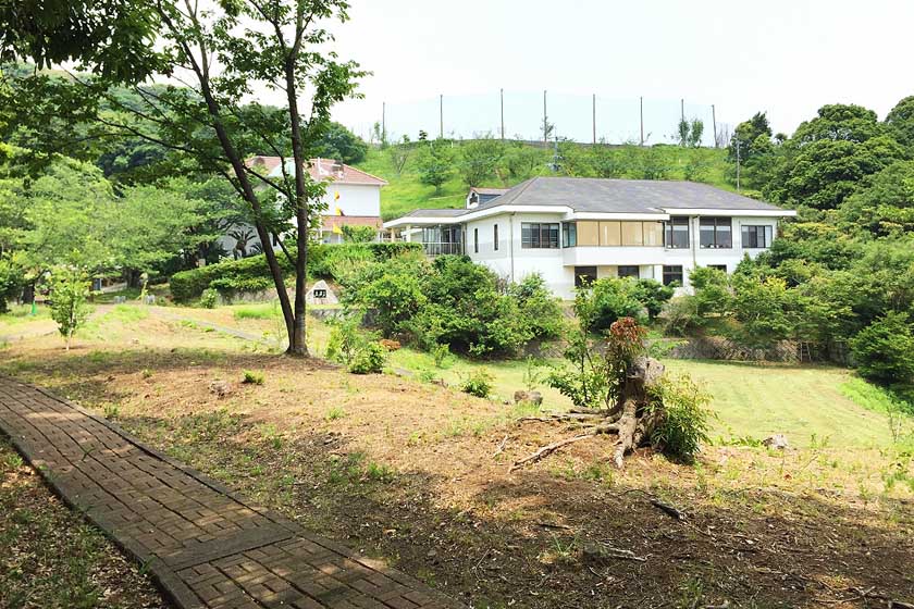 木々に囲まれた中に、能古博物館の白い2階建ての建物が立っています。