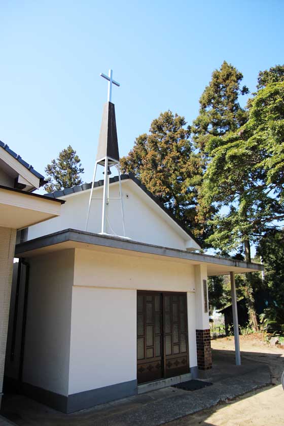 A cross stands above the white Nokonoshima Church building.